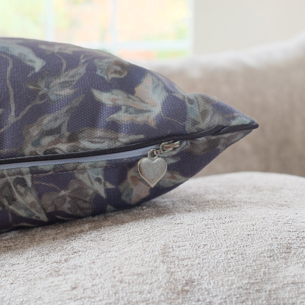 Floral-patterned pillow with a heart charm on a beige couch