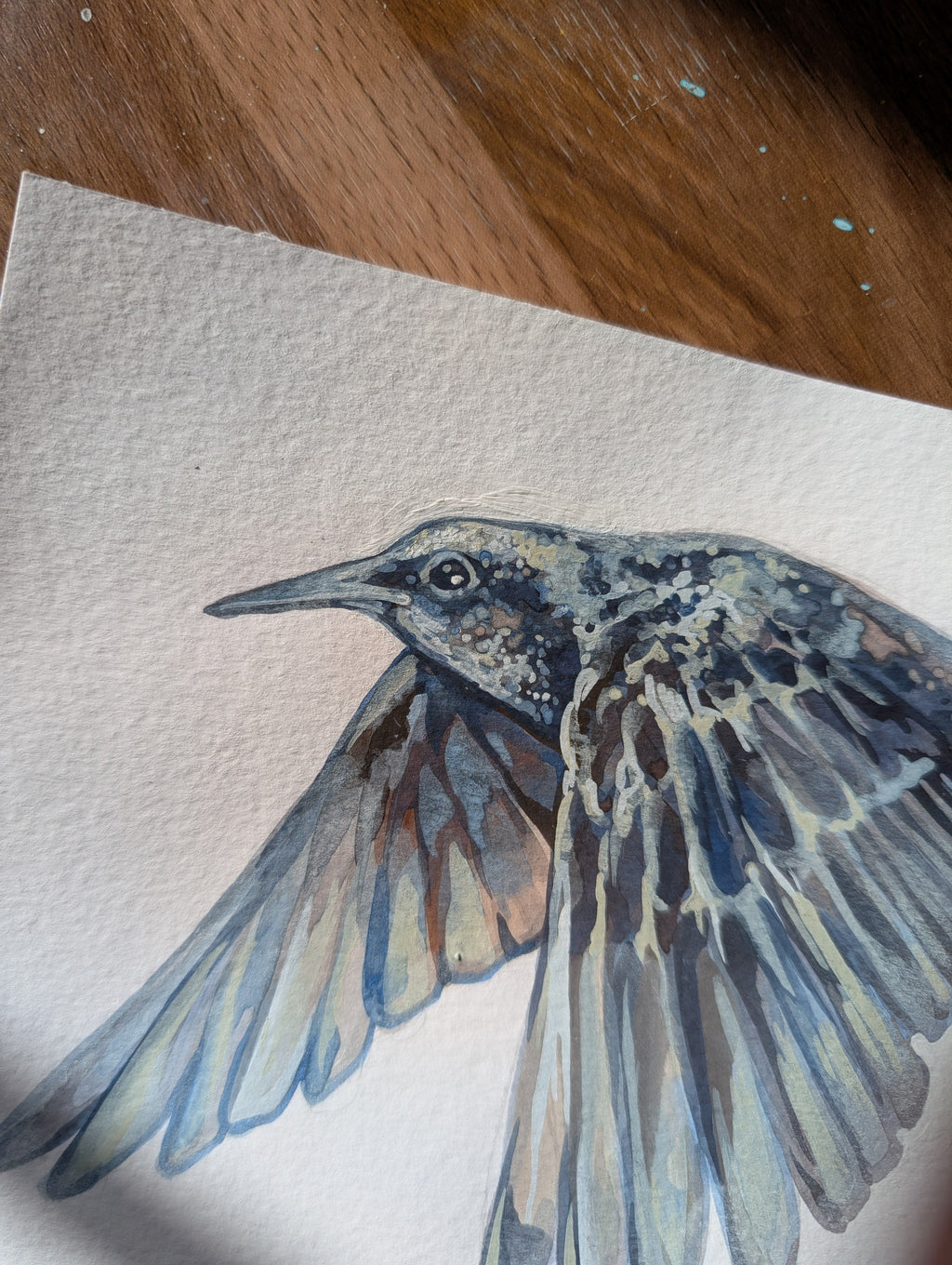 Artistic depiction of a bird on textured paper with a wooden surface below