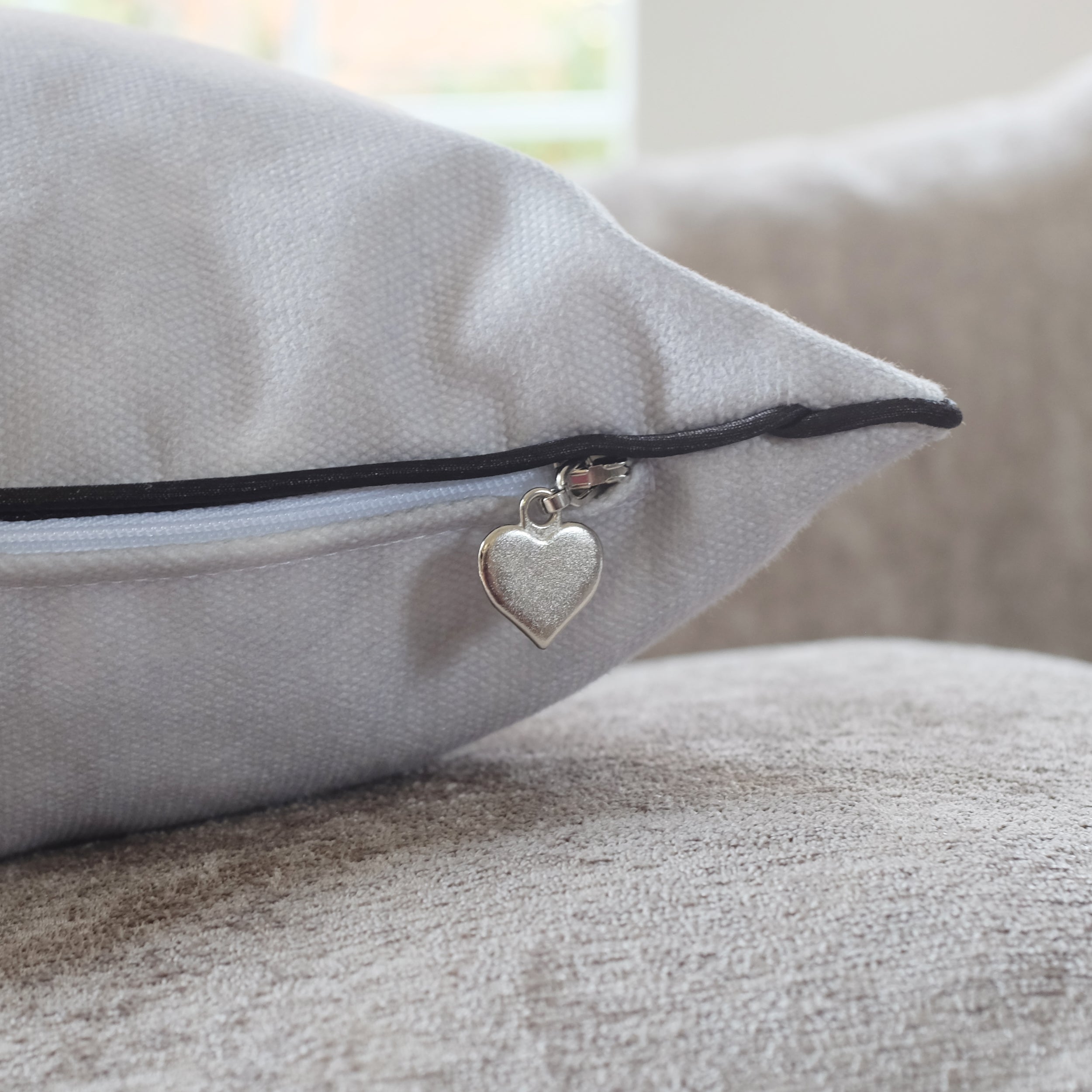 Gray pillow with a heart-shaped tag on a couch